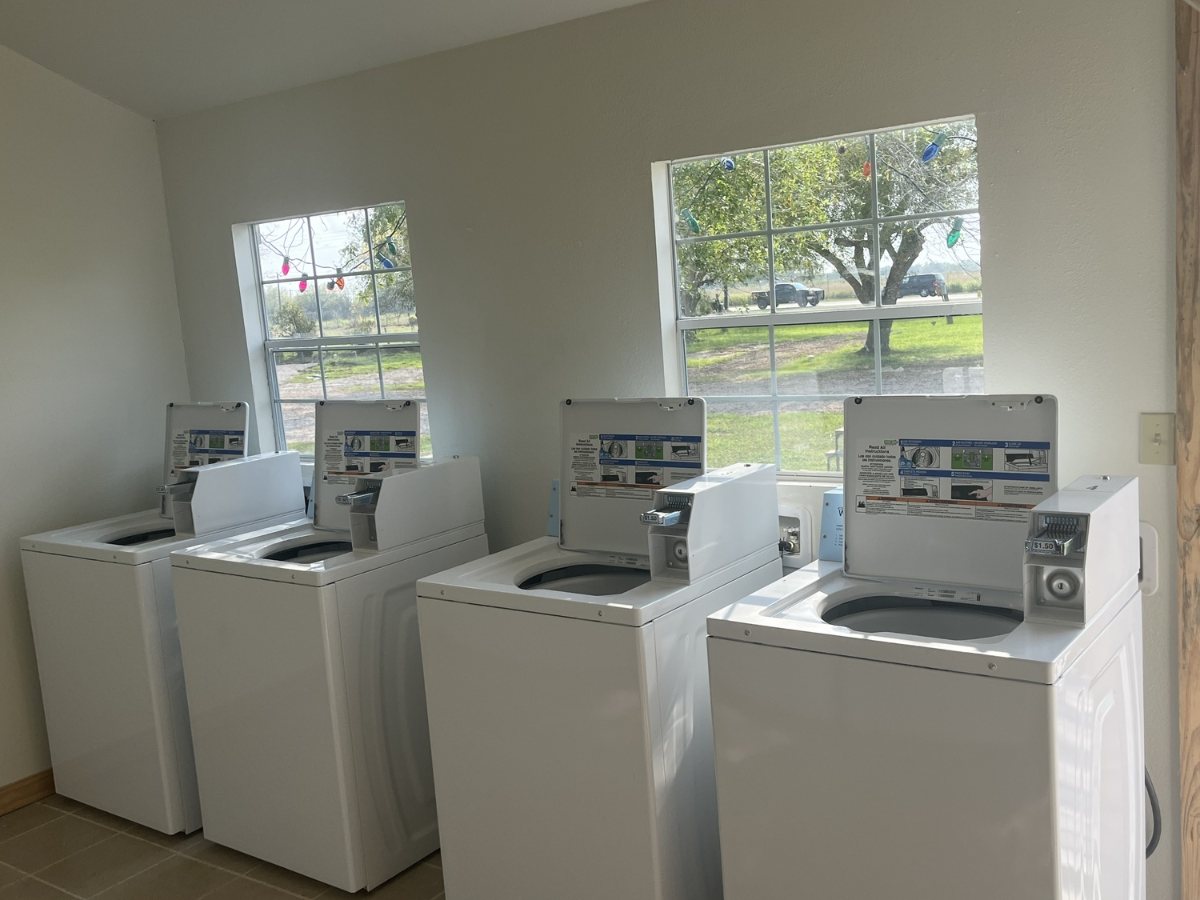 Four top-load washing machines in the on-site laundry room at The Texas Rose RV Park in Beeville, TX