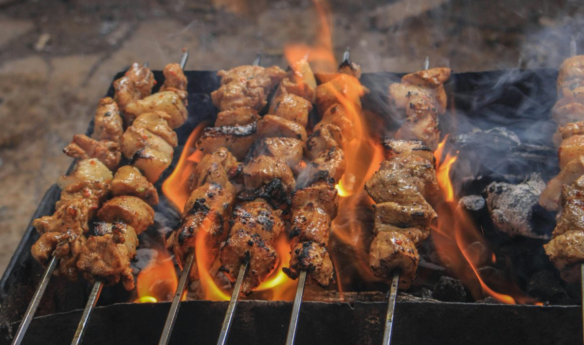 Skewers of marinated meat grilling over an open flame